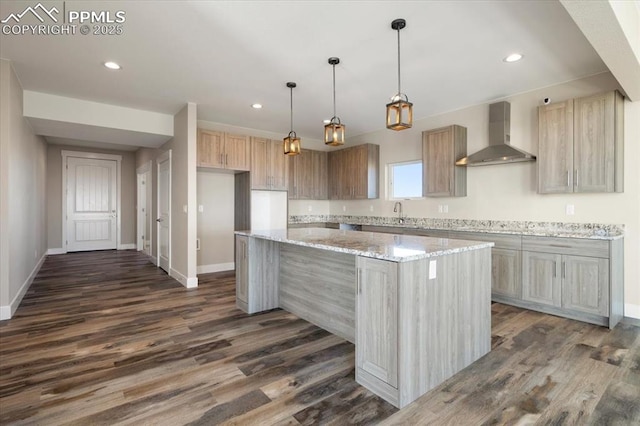 kitchen featuring wall chimney exhaust hood, dark hardwood / wood-style flooring, a center island, and light stone countertops