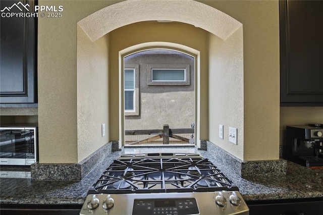 kitchen featuring stainless steel range with gas cooktop and dark stone countertops