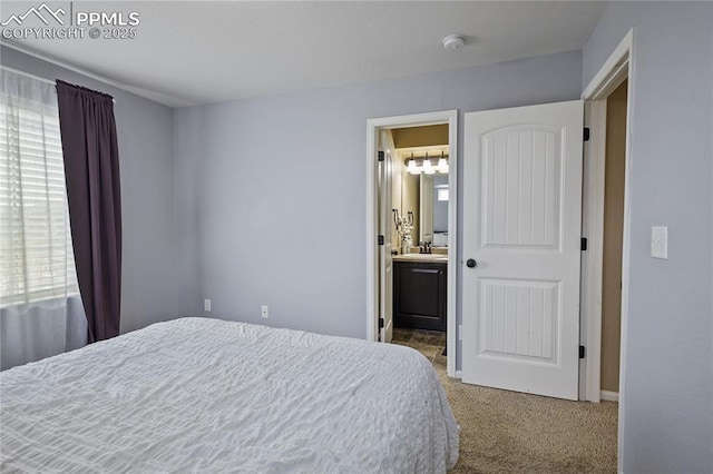 carpeted bedroom featuring sink, multiple windows, and ensuite bath