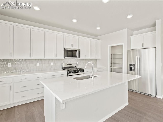 kitchen featuring sink, light hardwood / wood-style flooring, appliances with stainless steel finishes, an island with sink, and white cabinets