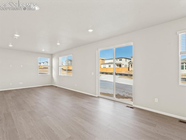 unfurnished room with a healthy amount of sunlight and hardwood / wood-style flooring