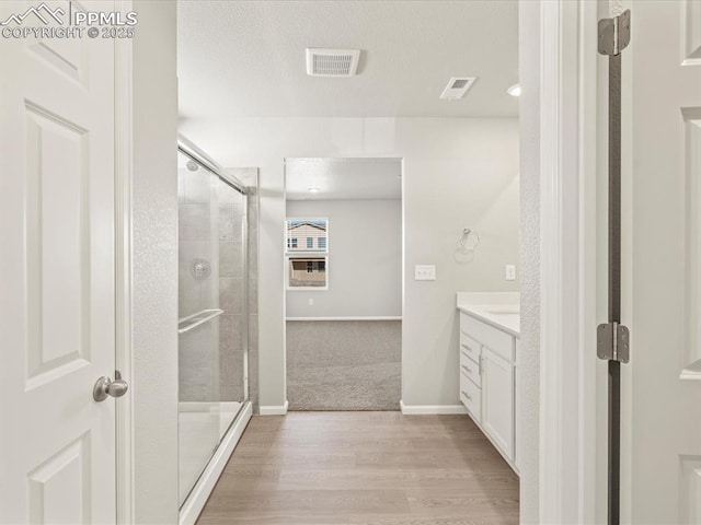 bathroom with a shower with door, wood-type flooring, and vanity