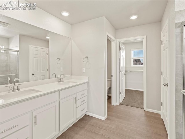 bathroom featuring toilet, vanity, a shower with door, and hardwood / wood-style flooring