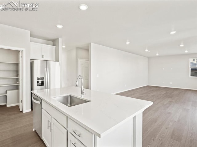 kitchen featuring white cabinetry, appliances with stainless steel finishes, a kitchen island with sink, light wood-type flooring, and sink