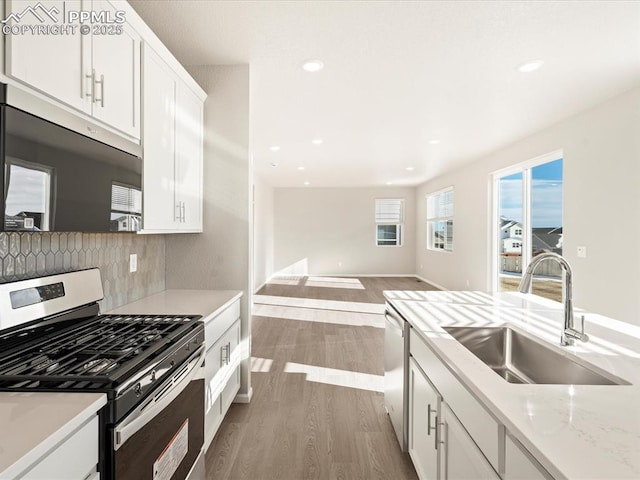 kitchen featuring white cabinetry, light hardwood / wood-style floors, stainless steel appliances, backsplash, and sink