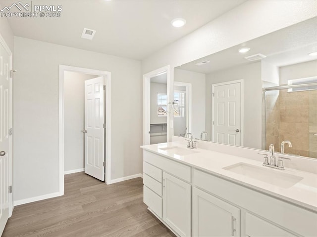 bathroom with a shower with door, hardwood / wood-style floors, and vanity