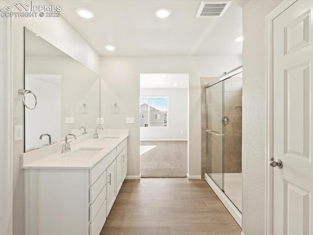 bathroom featuring hardwood / wood-style floors, walk in shower, and vanity