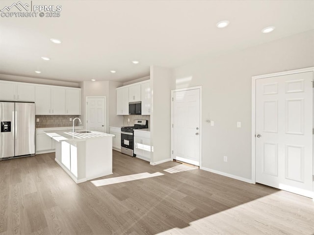 kitchen with white cabinetry, a center island with sink, stainless steel appliances, tasteful backsplash, and sink