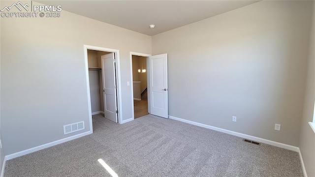 unfurnished bedroom with carpet, a walk in closet, and a closet