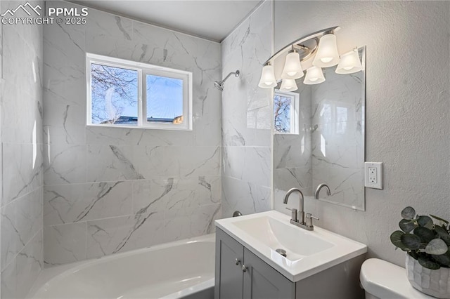 full bathroom featuring toilet, tiled shower / bath, plenty of natural light, and vanity