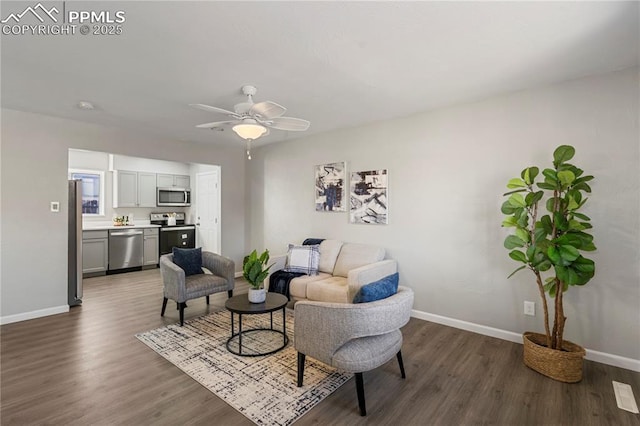 living room featuring ceiling fan and dark hardwood / wood-style flooring