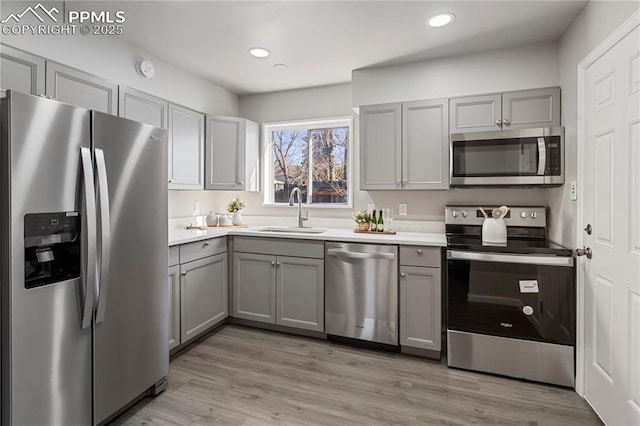 kitchen with light wood-type flooring, appliances with stainless steel finishes, sink, and gray cabinets