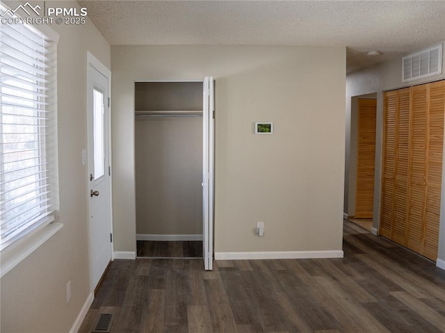 unfurnished bedroom with dark hardwood / wood-style flooring and a textured ceiling