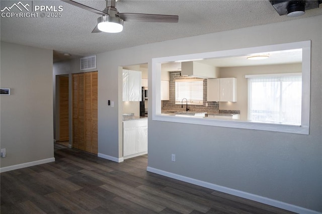 kitchen featuring sink, white cabinetry, a textured ceiling, decorative backsplash, and dark wood-type flooring