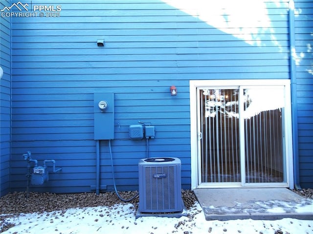 snow covered property entrance featuring central AC unit