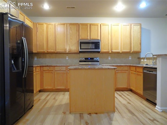 kitchen featuring light brown cabinets, a center island, stainless steel appliances, and sink