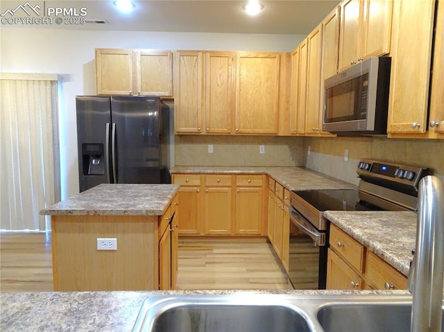 kitchen featuring a center island, light wood-type flooring, stainless steel appliances, and light brown cabinets