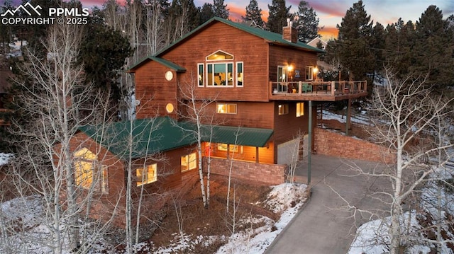 snow covered back of property with a deck and a garage