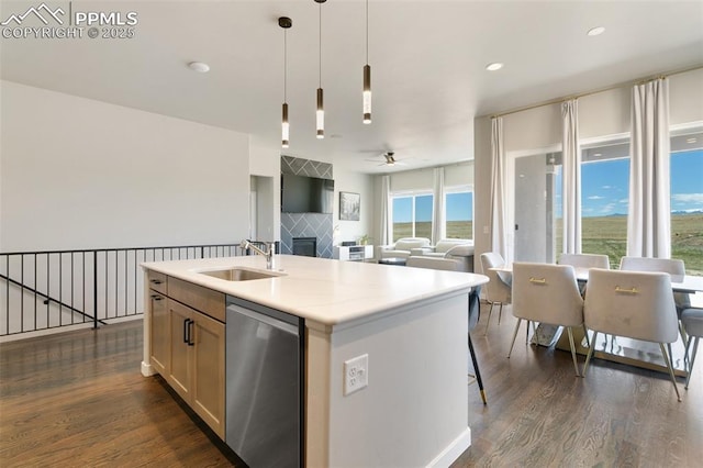 kitchen with a sink, light countertops, stainless steel dishwasher, dark wood finished floors, and pendant lighting