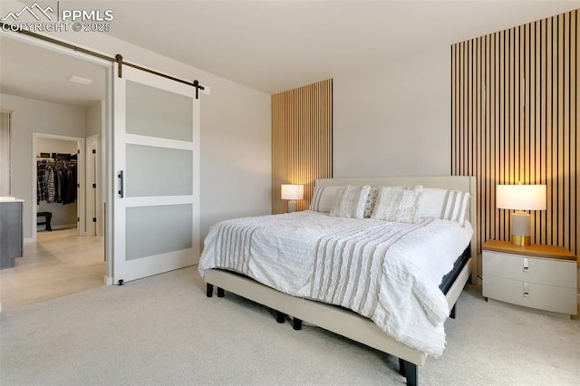 bedroom with light carpet, a spacious closet, a barn door, and a closet