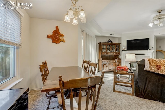 dining room with ceiling fan with notable chandelier, a wealth of natural light, and light colored carpet