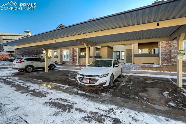 snow covered parking featuring a carport