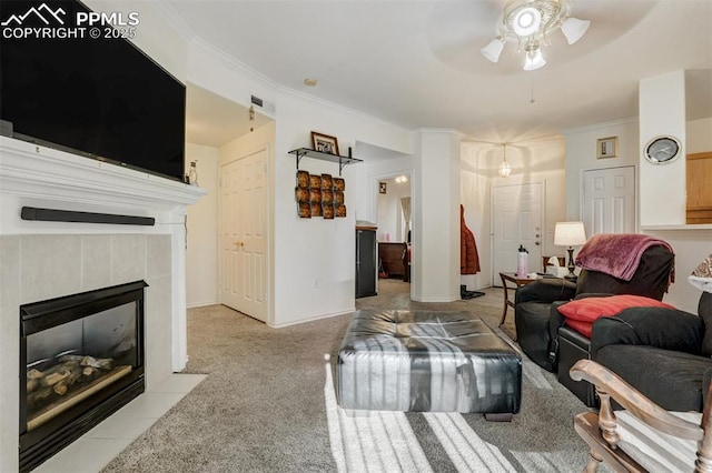 living room with ceiling fan, light colored carpet, ornamental molding, and a tile fireplace