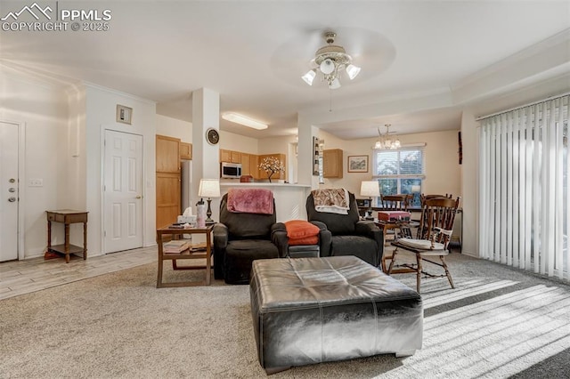 carpeted living room with ceiling fan with notable chandelier