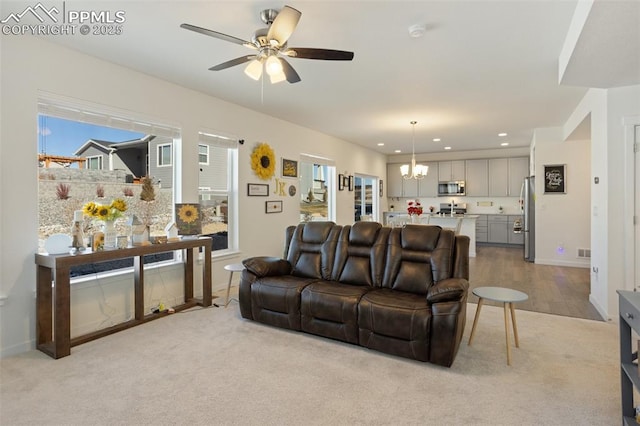 living room with light carpet and ceiling fan with notable chandelier