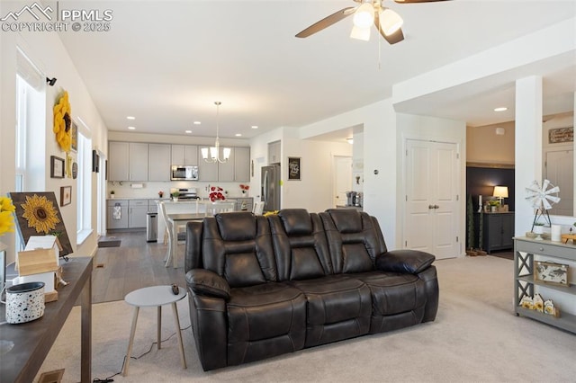 living room with light colored carpet and ceiling fan with notable chandelier