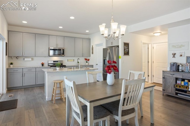 dining area with sink, a chandelier, and hardwood / wood-style flooring