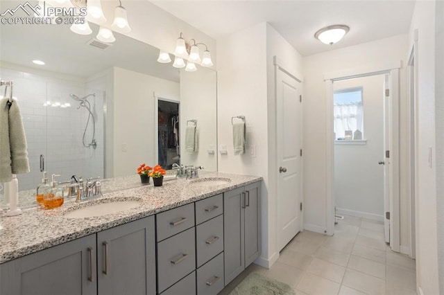 bathroom with tile patterned flooring, a shower with door, and vanity