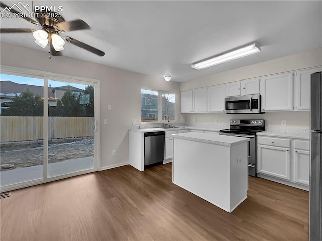 kitchen featuring a center island, white cabinetry, stainless steel appliances, and dark wood-type flooring