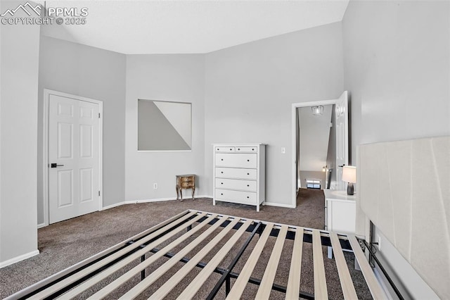 unfurnished bedroom with dark colored carpet and a towering ceiling