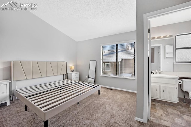 carpeted bedroom featuring sink, lofted ceiling, a textured ceiling, and ensuite bath