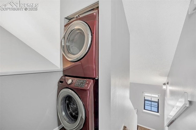 laundry area with a textured ceiling and stacked washer / dryer