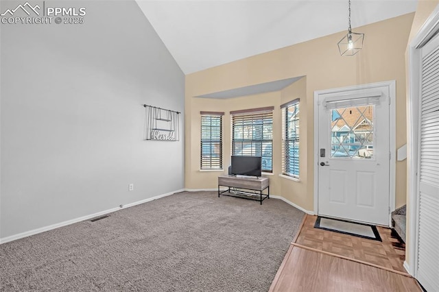 carpeted foyer entrance featuring high vaulted ceiling