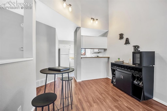 kitchen with white cabinets, white refrigerator, and light hardwood / wood-style flooring