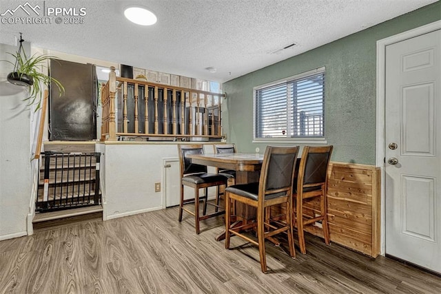 dining area featuring hardwood / wood-style flooring and a textured ceiling