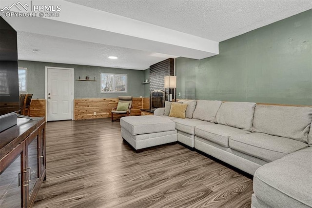 living room with hardwood / wood-style flooring, a brick fireplace, and a textured ceiling