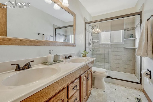 bathroom featuring vanity, toilet, a shower with shower door, and plenty of natural light