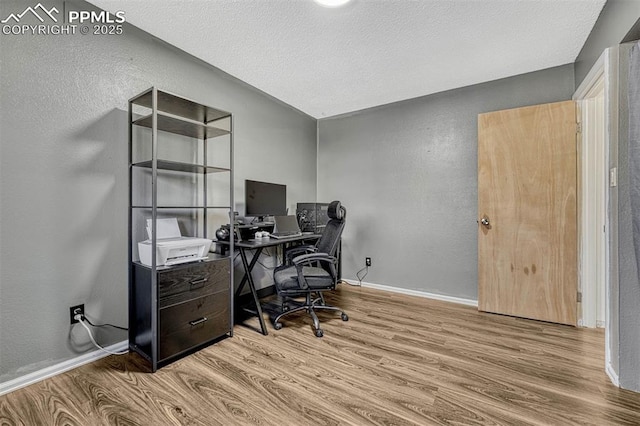 home office with a textured ceiling and light wood-type flooring