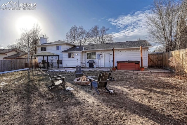 rear view of property with a gazebo, a hot tub, a patio area, and a fire pit