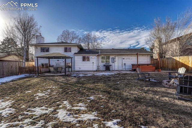 snow covered rear of property featuring a gazebo, a patio area, and a hot tub