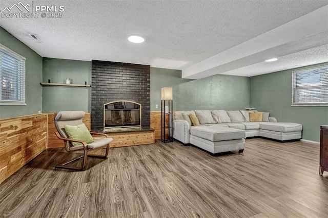 living room featuring a brick fireplace, a healthy amount of sunlight, and hardwood / wood-style floors