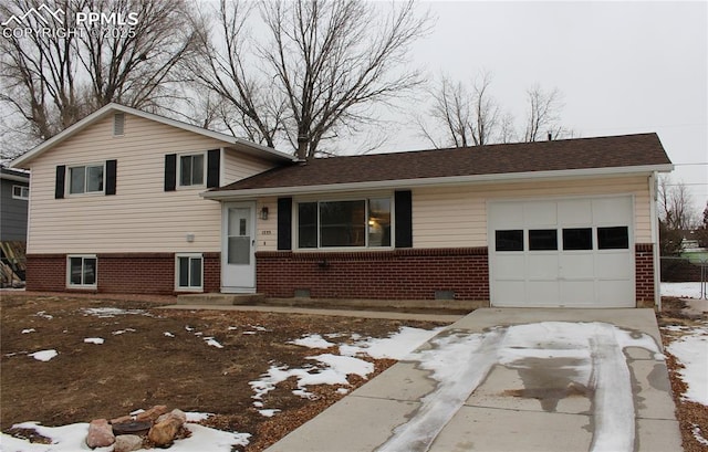 tri-level home with a garage, concrete driveway, and brick siding