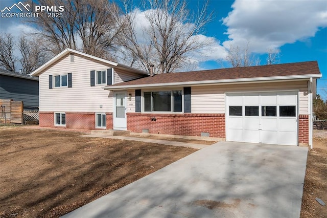 tri-level home featuring concrete driveway, brick siding, fence, and an attached garage