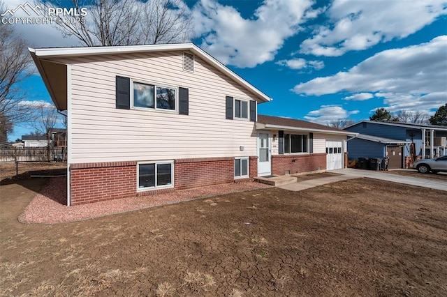 back of house with a garage, concrete driveway, and fence