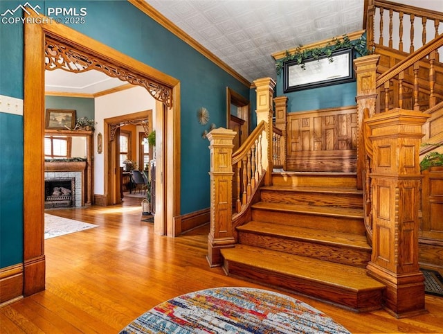 staircase with a fireplace, hardwood / wood-style floors, and ornamental molding