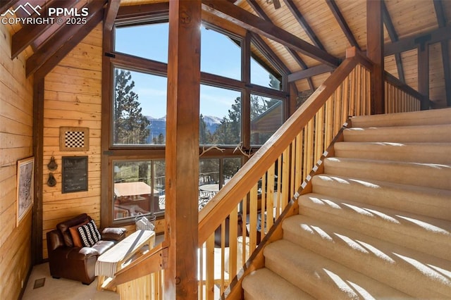 stairs with wood walls, wooden ceiling, lofted ceiling with beams, and a mountain view